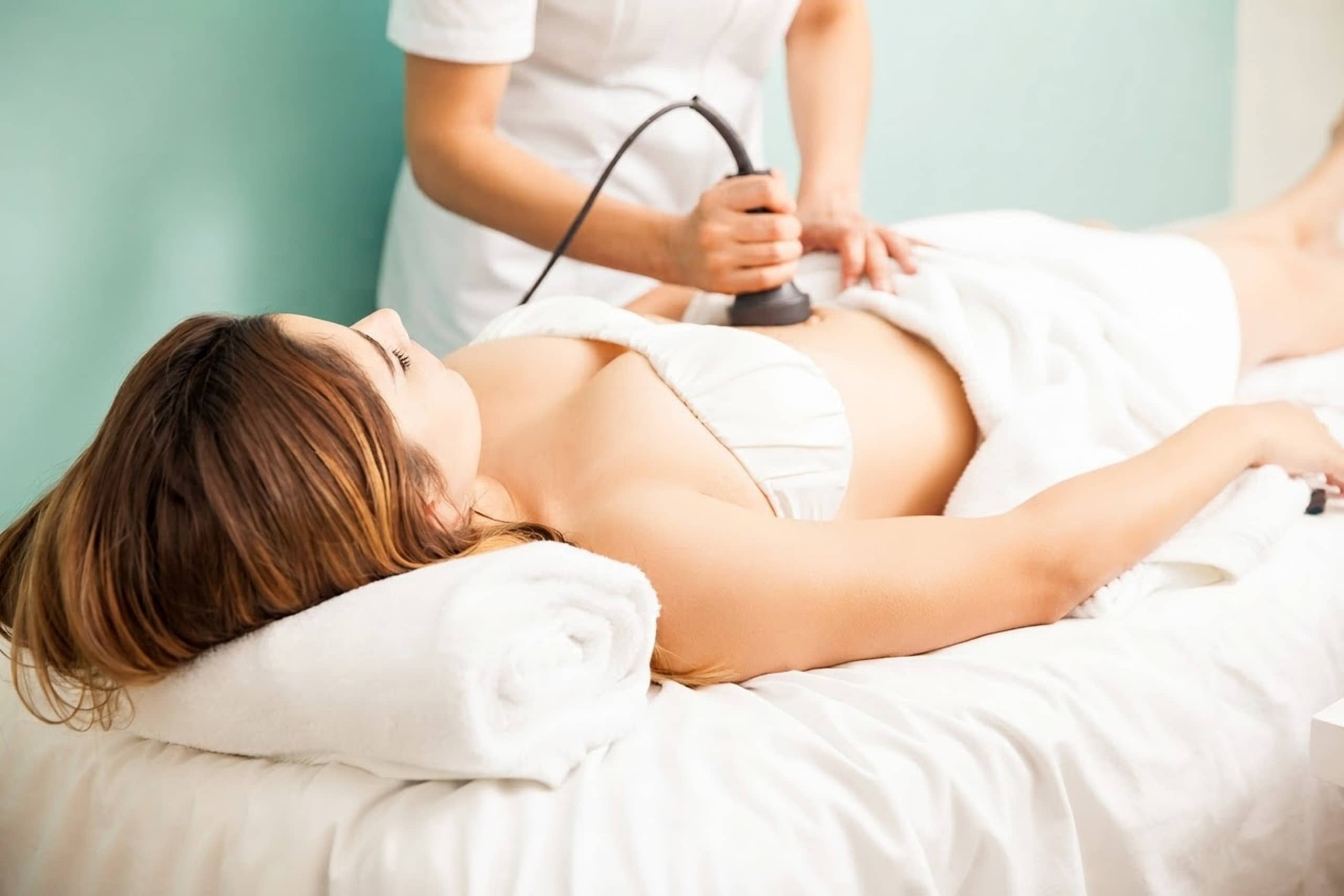 A therapist performing a body-contouring treatment on a client's abdomen